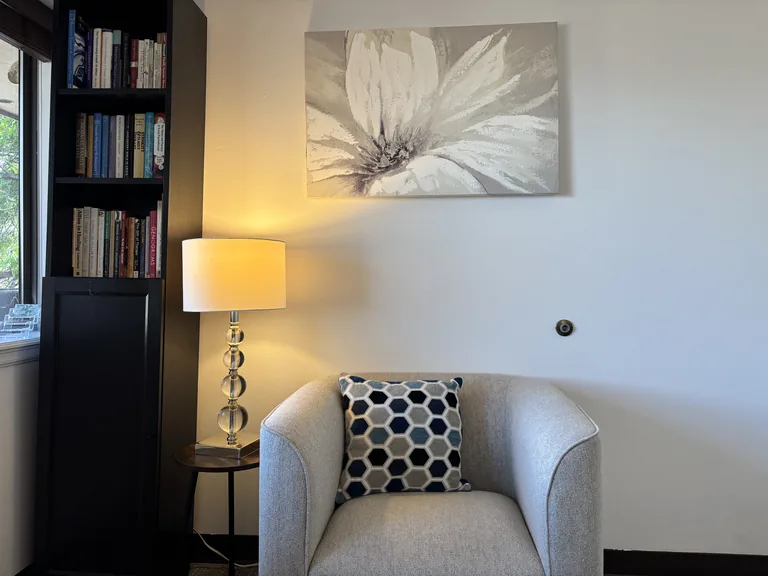 Reading nook with an armchair, bookshelf, and lamp in the Littleton couples therapy office