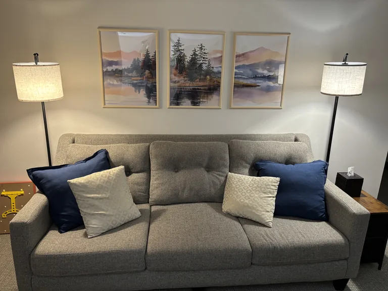 Waiting area couch beneath framed landscape art at Find Your Relationship